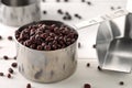 Raw, uncooked, dried adzuki red mung beans in metal measurement cups on white wooden table background Royalty Free Stock Photo