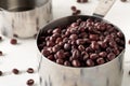 Raw, uncooked, dried adzuki red mung beans in metal measurement cups on white wooden table background Royalty Free Stock Photo