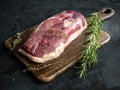 Raw uncooked duck breast with rosemary and thyme on wooden cutting board. Royalty Free Stock Photo