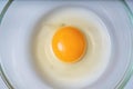 Raw uncooked egg in bowl. Yolk in center. Flat view from above.