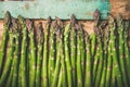 Raw uncooked green asparagus over rustic wooden tray background, close-up