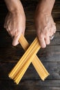 Raw uncooked Italian pasta spaghetti held in two hands over a dark wooden background Royalty Free Stock Photo