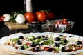 Raw uncooked pizza with pepperoni salami, black olives, basil and cheese Royalty Free Stock Photo