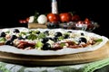 Raw uncooked pizza with pepperoni salami, black olives, basil and cheese Royalty Free Stock Photo