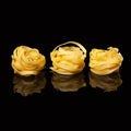 Raw uncooked tagliatelle nests on black background with reflection. Traditional Italian pasta Royalty Free Stock Photo