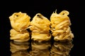 Raw uncooked tagliatelle nests on black background with reflection. Traditional Italian pasta Royalty Free Stock Photo