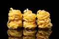 Raw uncooked tagliatelle nests on black background with reflection. Traditional Italian pasta Royalty Free Stock Photo