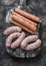 Raw uncooked turkey and spicy smoked paprika pork homemade sausages on a cutting board on dark background, top view. Food Royalty Free Stock Photo