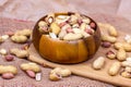 Raw unpeeled peanut nuts in nutshell in brown round wooden bowl on light paper background. Royalty Free Stock Photo