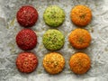 Raw vegan burgers made of beetroot, green peas, carrots, groats and herbs on white parchment prepared for baking, top view.