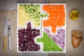 Raw vegetables carrots, peas, onions, cucumber, potatoes, beets cut into cubes lie on puzzles in the form of puzzles Royalty Free Stock Photo