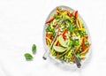 Raw vegetables slaw salad on light background, top view. Zucchini, bell peppers, carrots, squash, green peas salad.