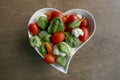 Heart shaped plate with assorted fresh vegetables, top view.
