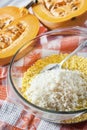Raw washed millet and rice in a glass pan in the process of preparing milk porridge with pumpkin and raisins Royalty Free Stock Photo