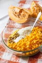 Raw washed millet, rice, raisins and pumpkin in a glass pan in the process of cooking milk porridge Royalty Free Stock Photo