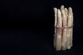 Raw white asparagus tied with brown loose rope over a black isolated background