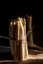 Raw white asparagus tied with brown loose rope over a rustic background with its reflection