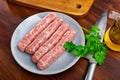 Raw white botifarra sausages on plate with knife and fresh parsley