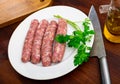 Raw white botifarra sausages on plate with knife and fresh parsley