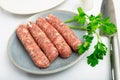 Raw white botifarra sausages on plate with knife and fresh parsley