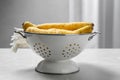 Raw white carrots in colander on grey table