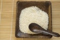 ÃâRaw white rice on dark wooden plate with spoon, bamboo Mat background, top view, veganism, organic food, world food day Royalty Free Stock Photo