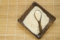 Raw white rice on wooden plate and wooden spoons with rice on bamboo napkin for healthy eating, vegetarianism, top view, flat lay