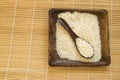 Raw white rice on wooden plate and wooden spoons with rice on bamboo napkin for healthy eating, vegetarianism, top view, flat lay