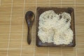 Raw white rice on wooden plate and wooden spoons with rice on bamboo napkin for healthy eating, vegetarianism, top view, flat lay