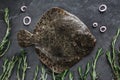 Raw whole flounder fish with rosemary, onions and spices on dark stone background. Creative layout made of fish, top view