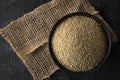 Raw, whole, unprocessed quinoa seed in bowl on wood board