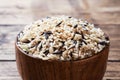 Raw wild rice in a wooden bowl. Raw rice grits on a wooden background. Copy space