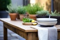 raw wood table with stoneware bowls, linen runners, and fresh herbs in pots Royalty Free Stock Photo