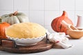 Raw yeast dough with pumpkin in white bowl covered with towel on the floured kitchen table, recipe idea. Concept home baking bread Royalty Free Stock Photo