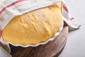 Raw yeast dough with pumpkin in white bowl covered with towel on the floured kitchen table, recipe idea. Concept home baking bread Royalty Free Stock Photo