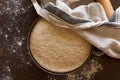 Raw yeast dough resting and rising in large metal bowl covering with linen towel Royalty Free Stock Photo