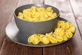 Raw yellow pasta conchiglie on brown wood