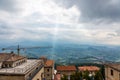 A ray of sun breaks through the dark clouds against the backdrop of the mountains in San Marino