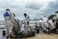 Workers remove and clean up crude oil spilled from Prao Bay