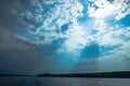 The rays of God in the river landscape. The sun`s rays shine through the clouds over the water surface and the shore. Copy space Royalty Free Stock Photo