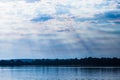 The rays of God in the river landscape. The sun`s rays shine through the clouds over the water surface and the shore. Copy space Royalty Free Stock Photo