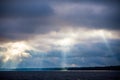 The rays of God in the river landscape. The sun`s rays shine through the clouds over the water surface and the shore. Copy space Royalty Free Stock Photo