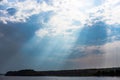 The rays of God in the river landscape. The sun`s rays shine through the clouds over the water surface and the shore. Copy space Royalty Free Stock Photo