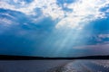 The rays of God in the river landscape. The sun's rays shine through the clouds over the water surface and the shore Royalty Free Stock Photo