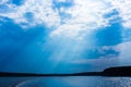 The rays of God in the river landscape. The sun's rays shine through the clouds over the water surface and the shore Royalty Free Stock Photo