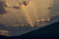 Rays of light filter through the clouds in a beautiful sunset behind the mountain Royalty Free Stock Photo