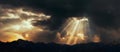 Rays of light shining through dark clouds over mountains. Cinematic scene Royalty Free Stock Photo