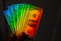 Rays of a rainbow on a man's hand with a bundle of dollars. Royalty Free Stock Photo