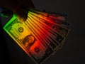 Rays of a rainbow on a man's hand with a bundle of dollars. Royalty Free Stock Photo