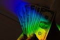 Rays of a rainbow on a man's hand with a bundle of dollars. Royalty Free Stock Photo